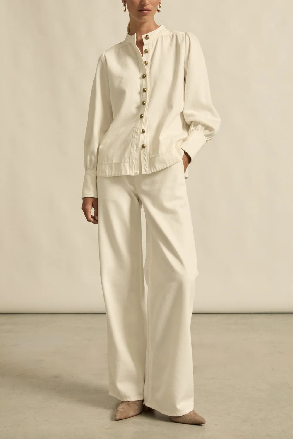 Person wearing a cream-colored outfit with wide-leg pants against a neutral background